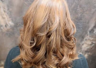 Cheveux blonds bouclés de dos, salon MD Coiffure